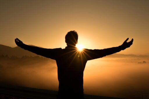 silhueta de um homem no penhasco ao pôr do sol