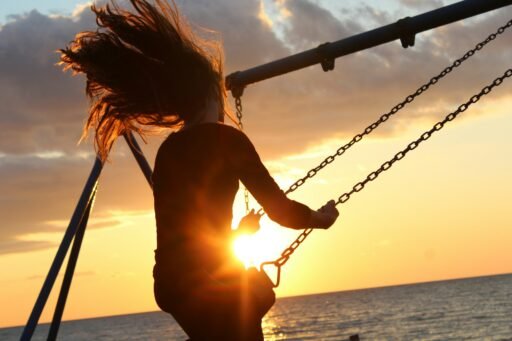 mulher sentada no balanço durante o pôr do sol