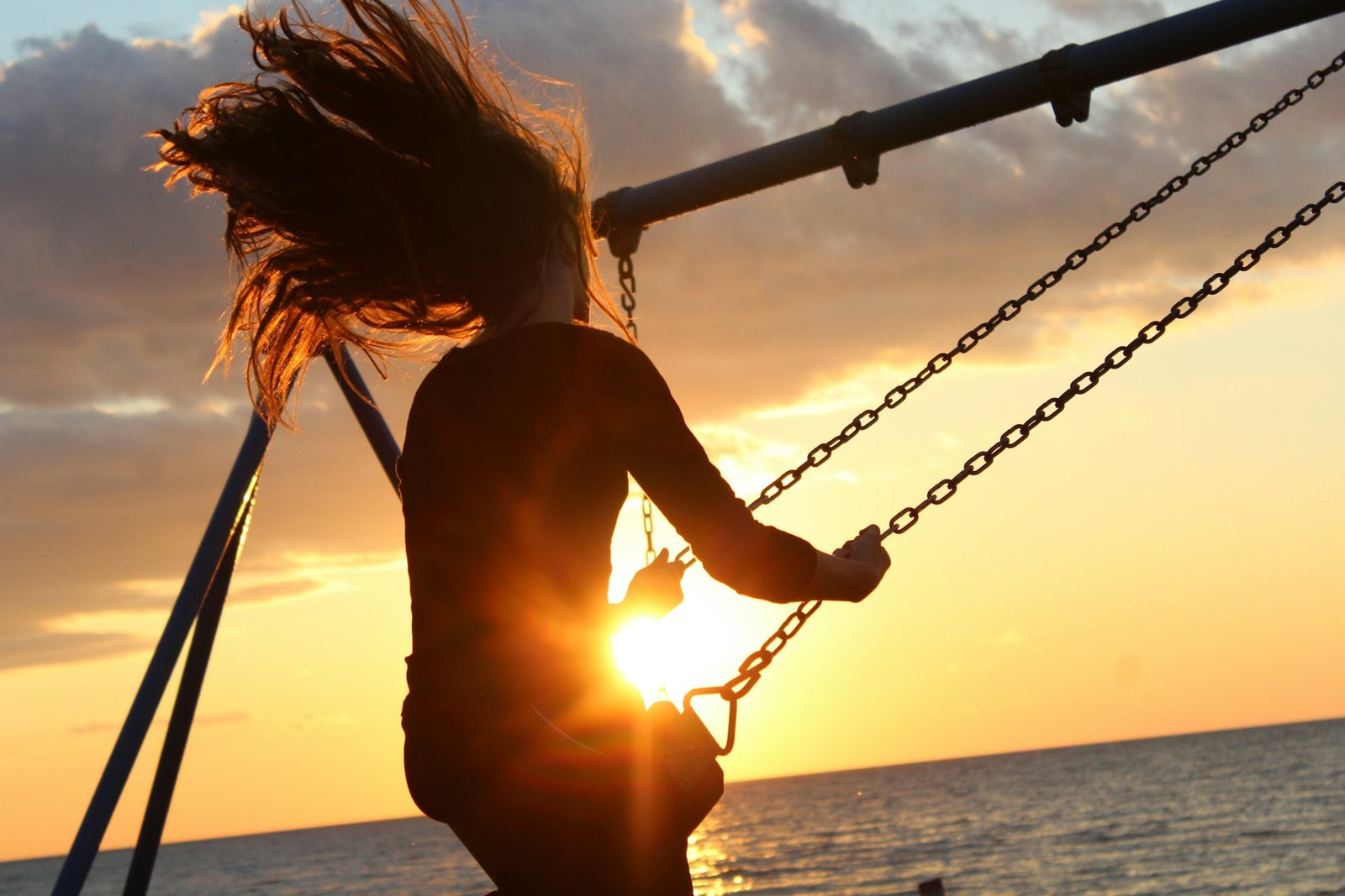 mulher sentada no balanço durante o pôr do sol